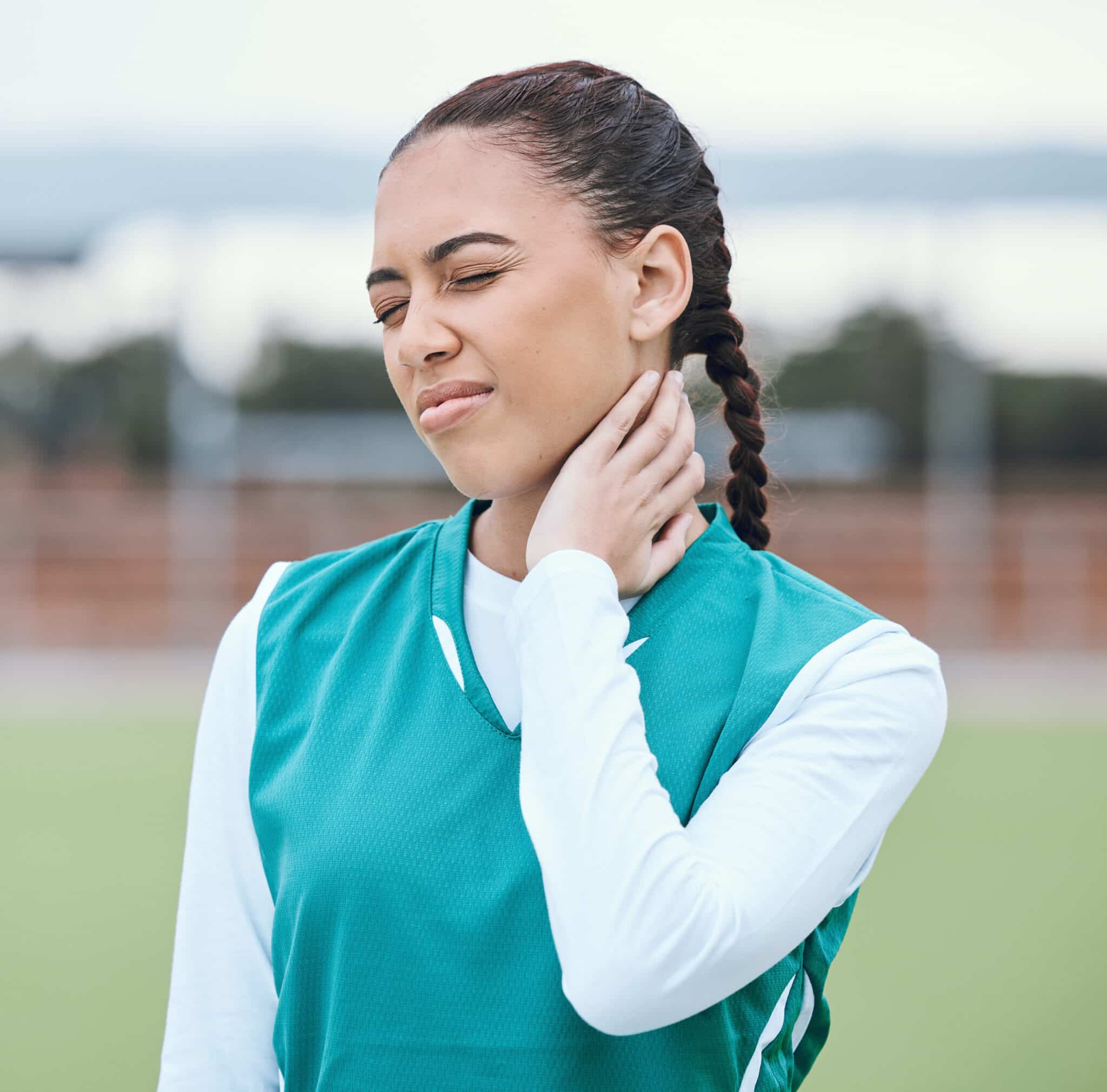 Athlete holding her neck wincing in pain from stiff neck or neck injury.