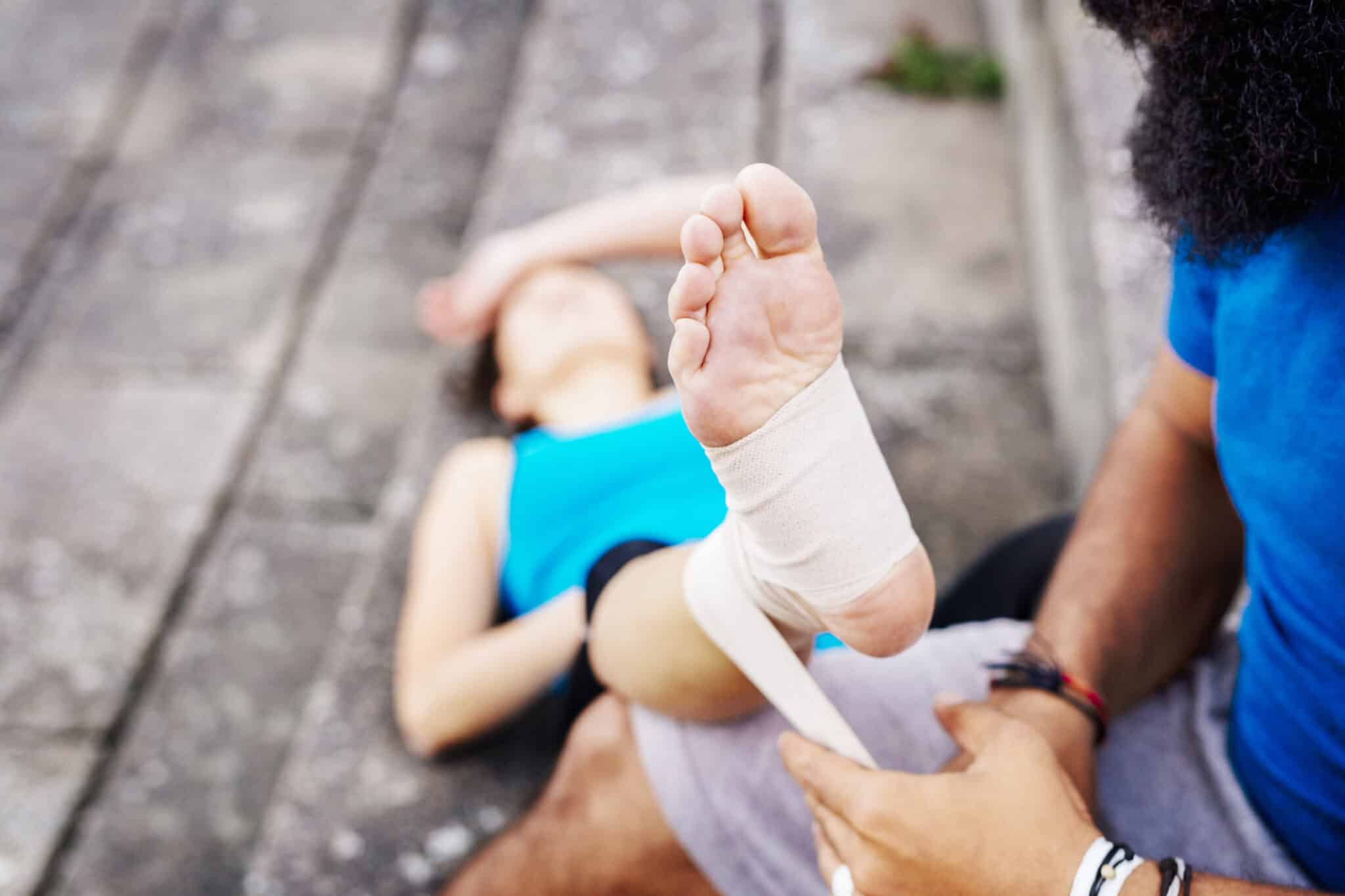 man wrapping foot of woman with sprained ankle in bandage