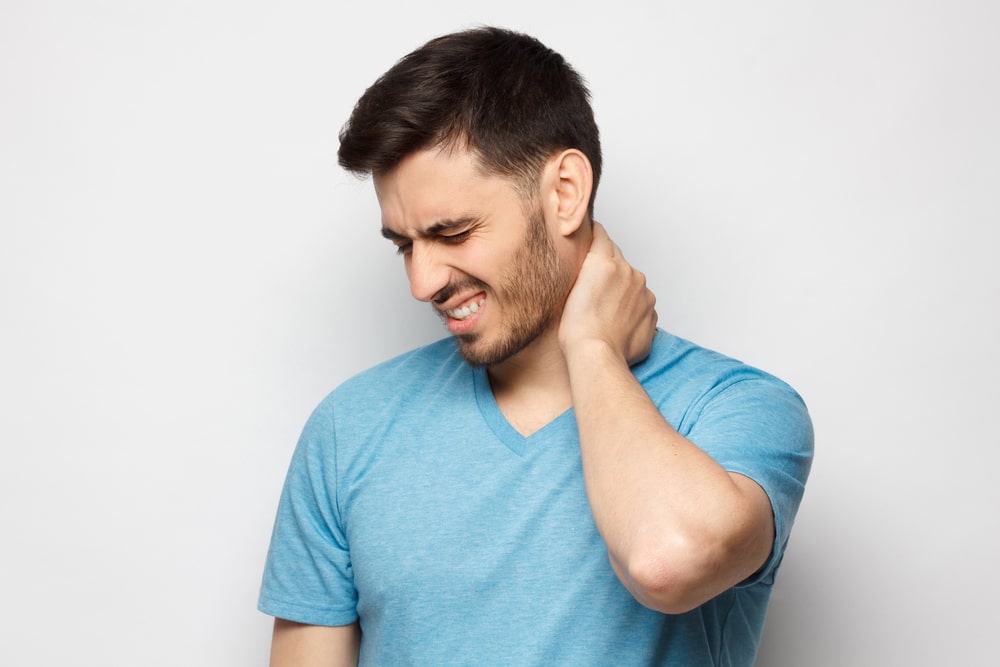 A man in need of spinal cord stimulation holding the back of his neck in pain