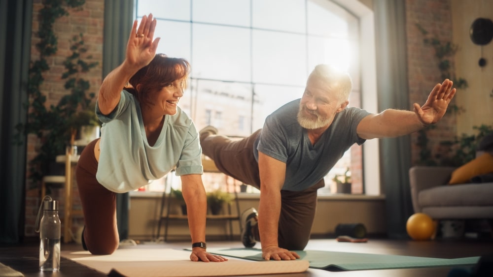 Senior couple on floor doing exercises to protect their joint health as they age.