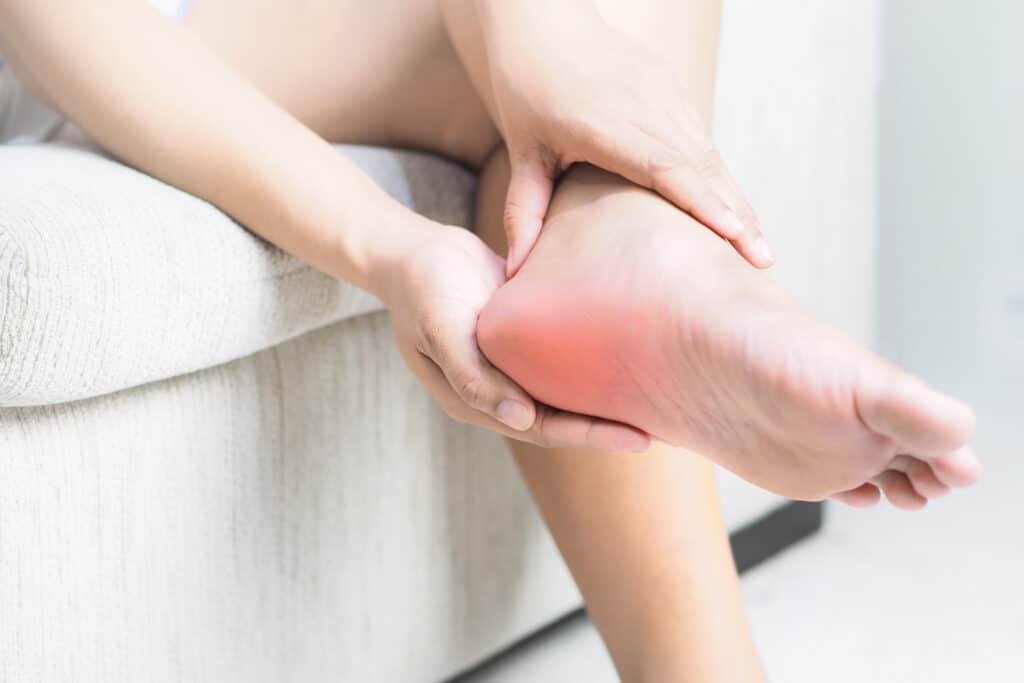Woman holding foot experiencing heel pain from plantar fasciitis