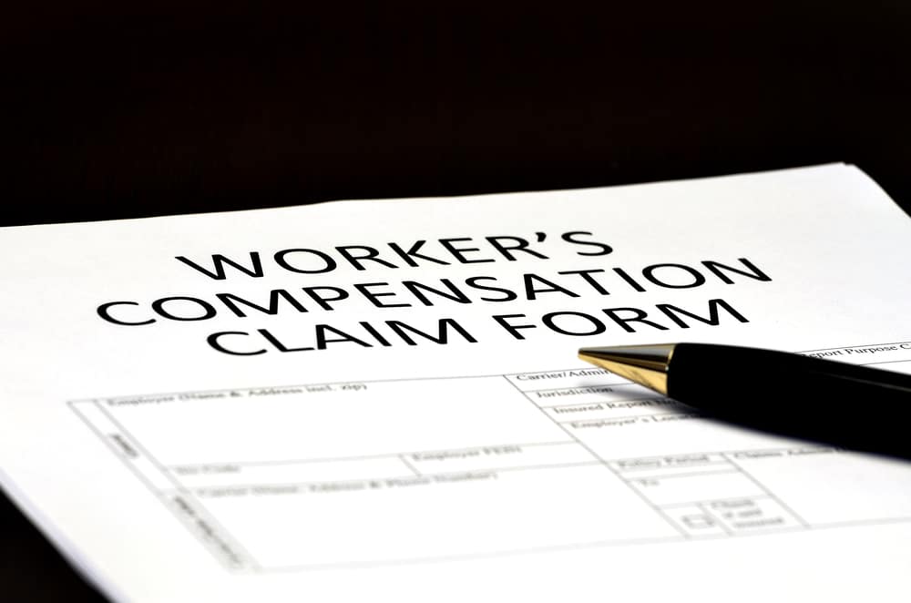 A pen and piece of paper that says "Workers' Compensation Claim Form"