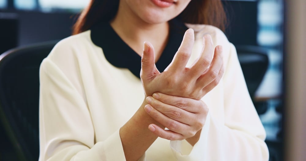 Woman holding her hand in discomfort due to cramping