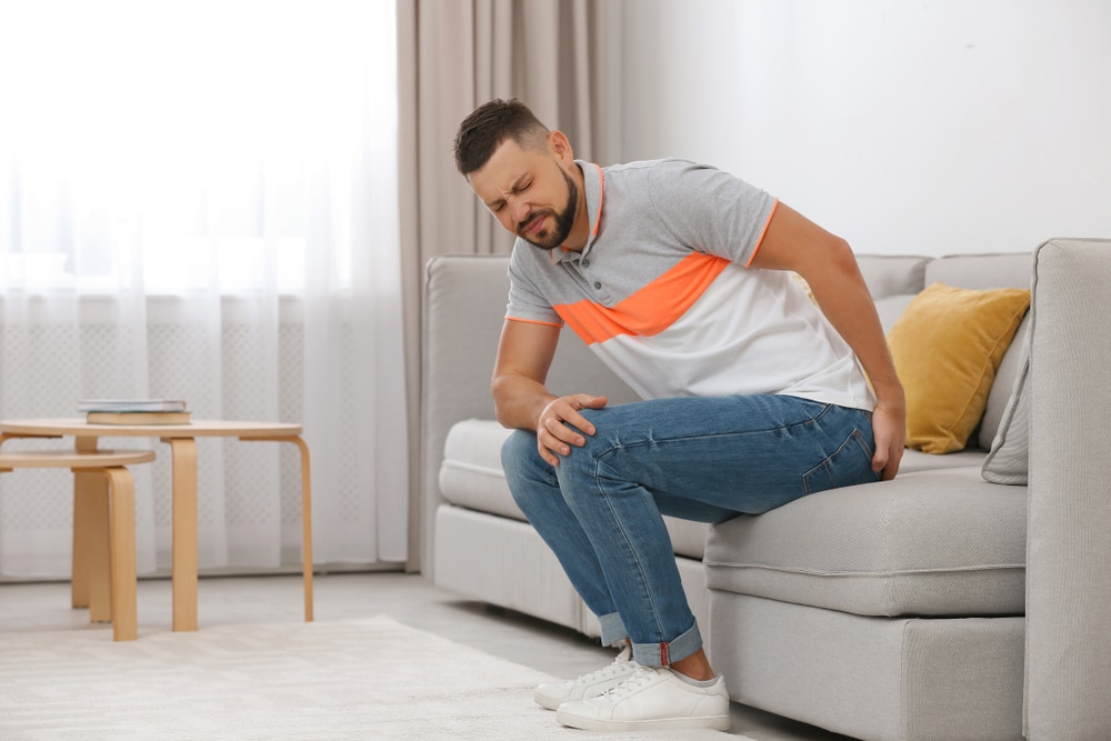 Man sitting on couch experiencing pain from his sciatic nerve