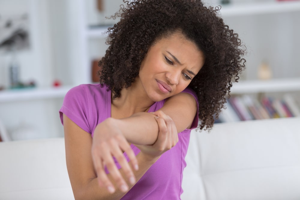 Woman holding her elbow in pain, representing a common pickleball injury that may need sports medicine care.